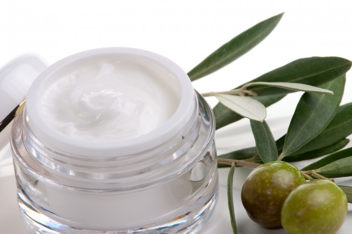 face care closeup of jar of moisturizing face cream and twig with green olives