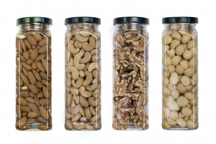 macadamia nuts walnuts cashews almonds packed in plastic jars on the background